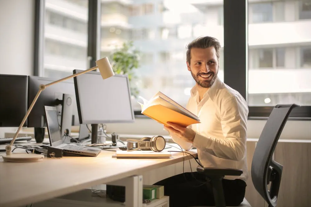 smiling man looking over his shoulder sitting at desk